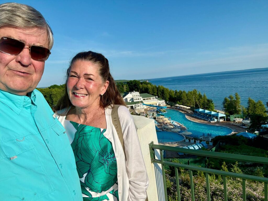Couple smiling by seaside resort and pool.