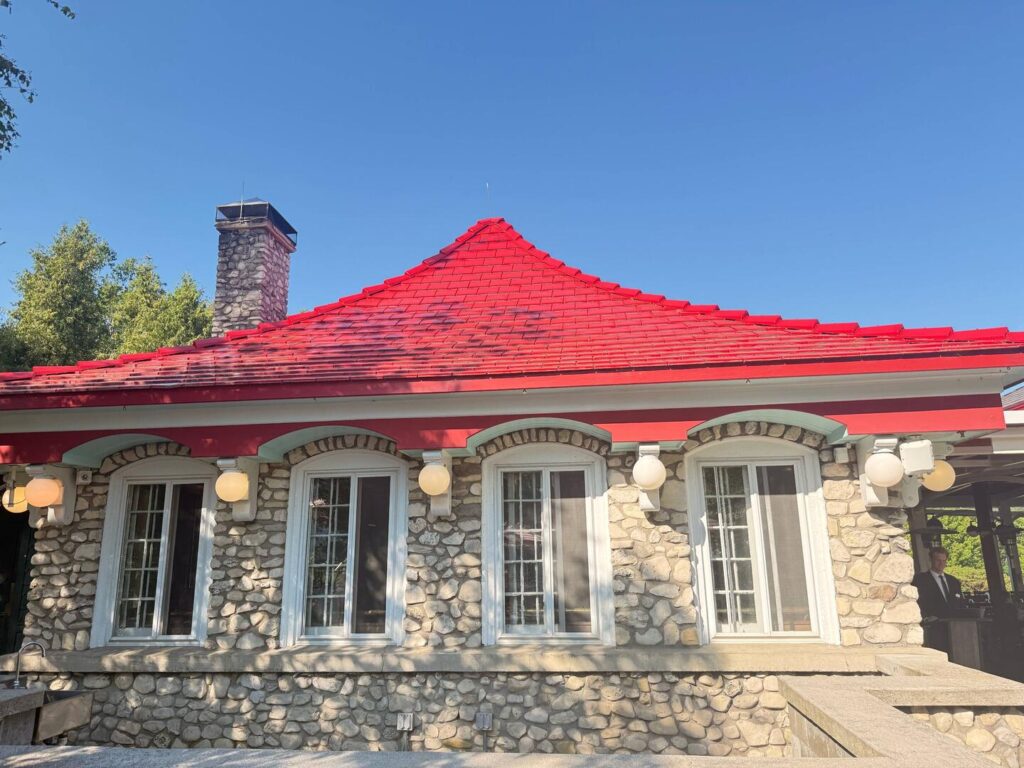 Stone building with bright red roof and chimney.