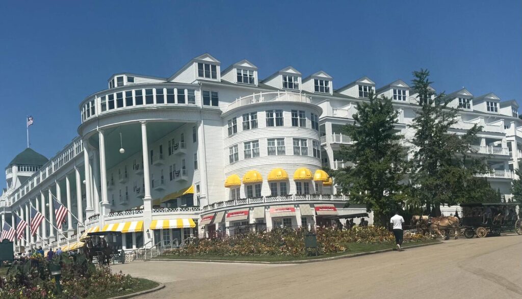 Historic white hotel with yellow awnings and horse carriage.