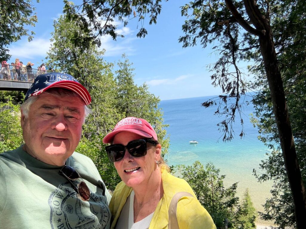 Couple posing with lake and trees in background.