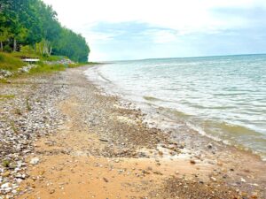 Rocky lakeshore with trees and clear water.