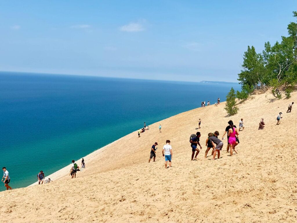 People climbing a sandy hill by the sea