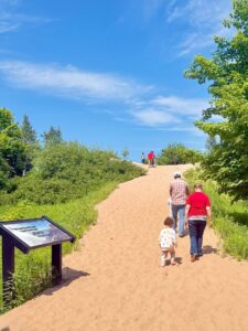Family walking on a sandy hill in nature.