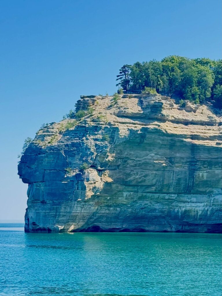 Rocky cliff by turquoise water under blue sky
