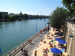 People relaxing on riverside urban beach.