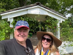 Couple smiling in garden under gazebo.