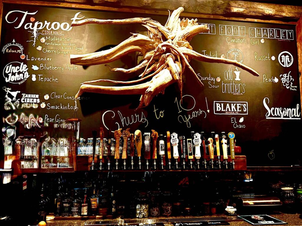 Rustic cider bar with taps and menu on chalkboard.