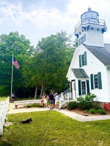 Lighthouse with American flag and visiting tourists.