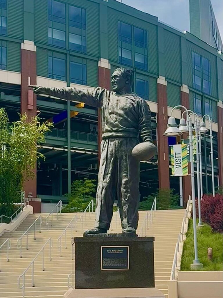 Statue of man pointing, holding football.