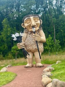 Large wooden troll sculpture in forest clearing.