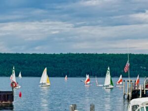 Sailboats on a calm lake under cloudy sky.