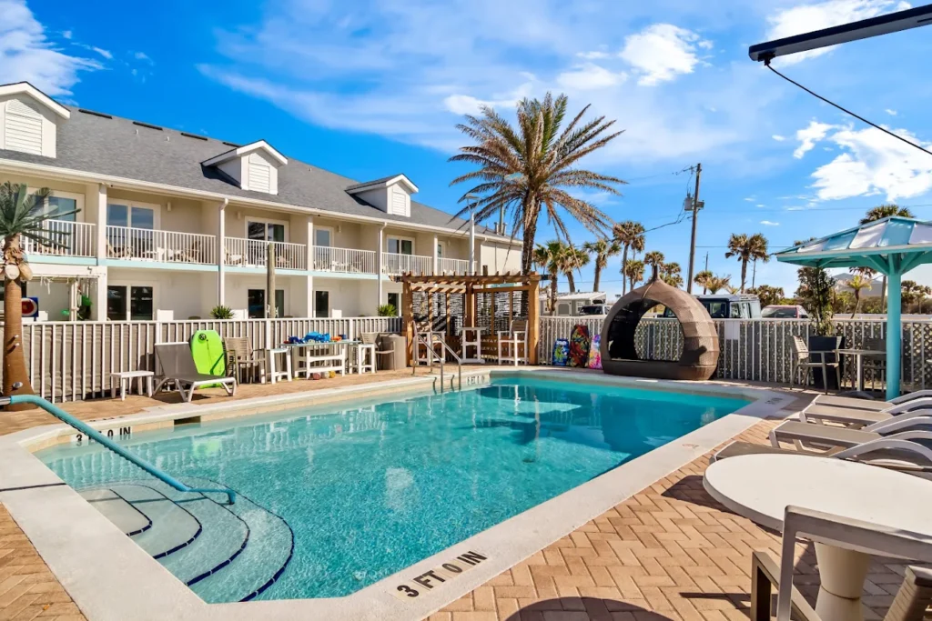 Outdoor pool with sun loungers and palm trees.