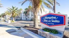 Hampton Inn & Suites hotel exterior with palm trees.