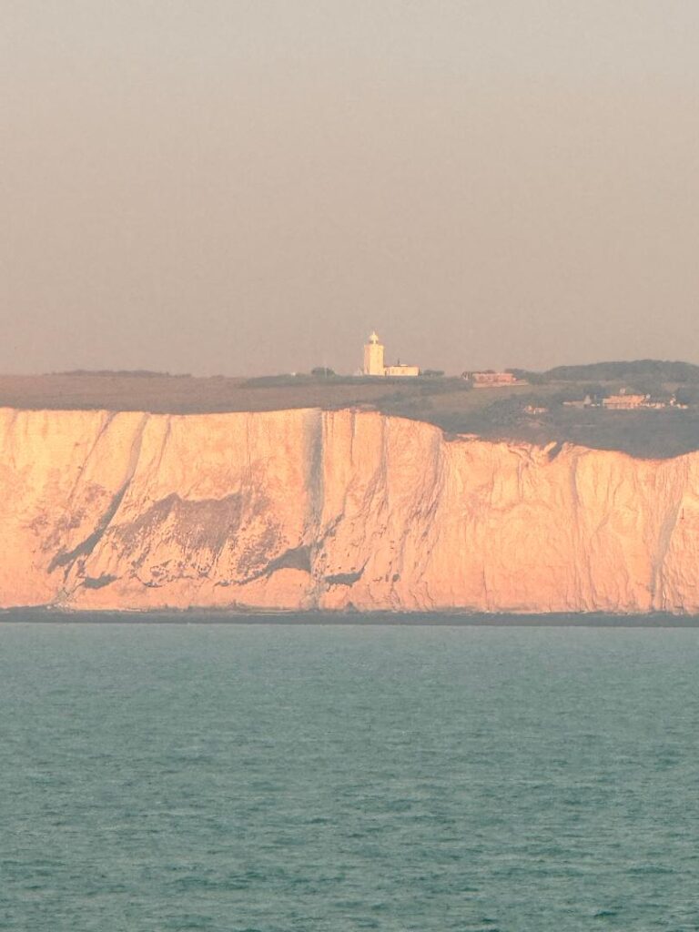 White cliffs with lighthouse during sunset.