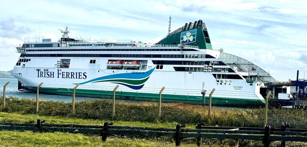 Irish Ferries ship docked under cloudy sky.
