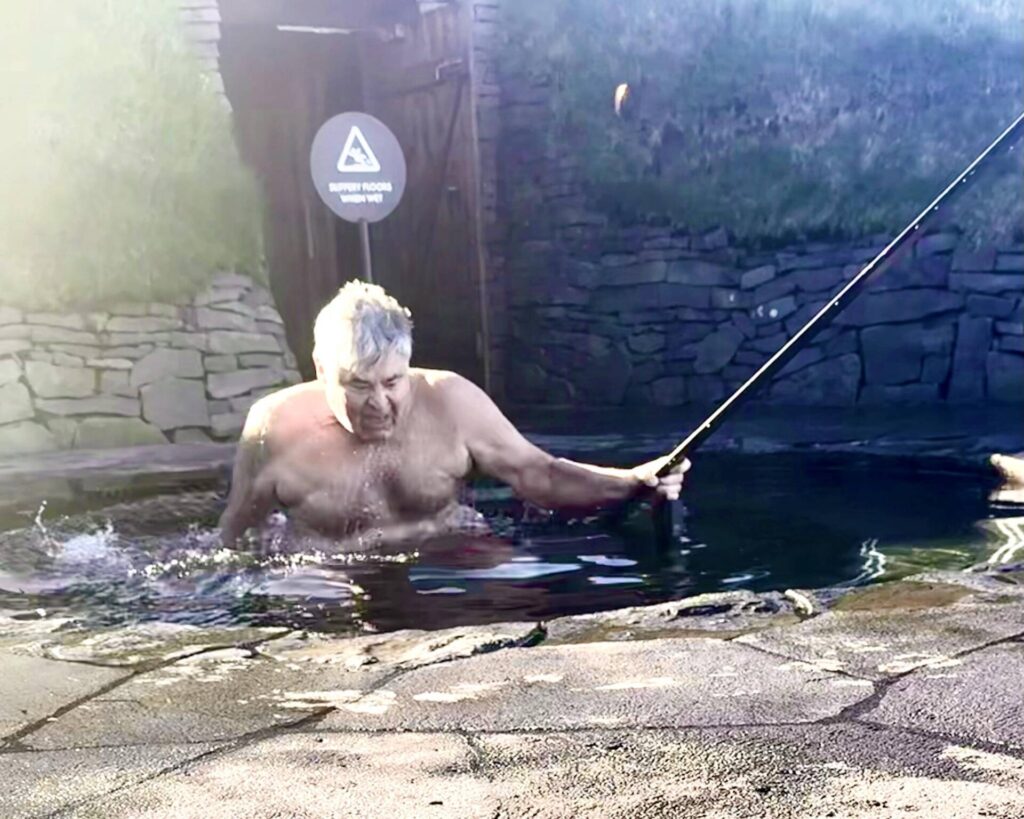 Man fishing in small pond with a rod.