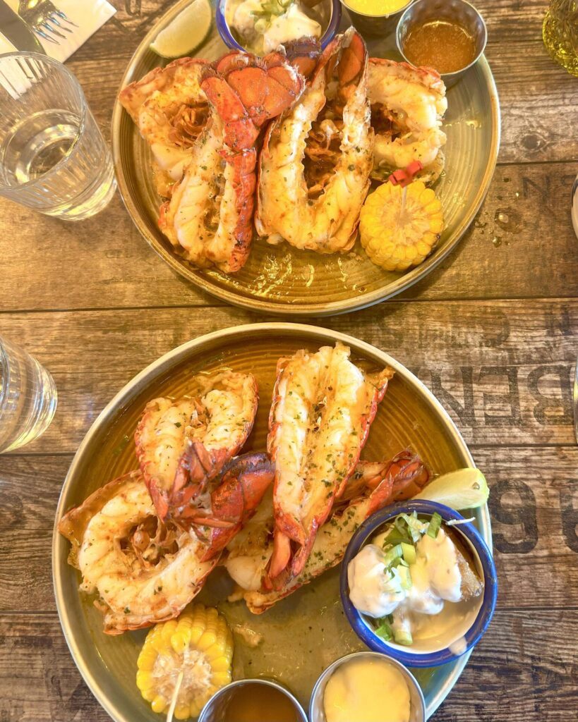 Grilled lobster tails with dipping sauces and corn.