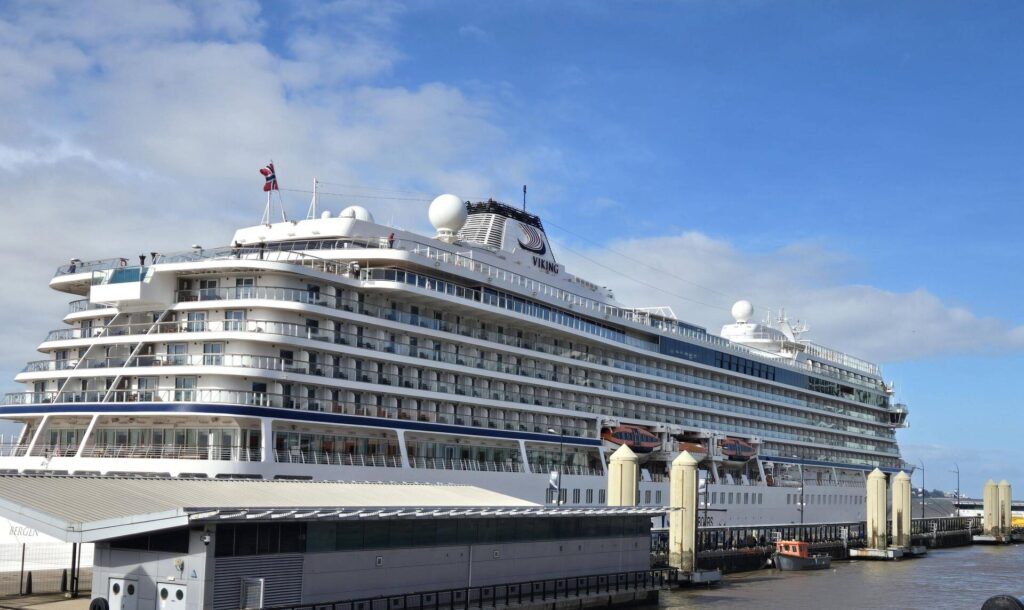Large cruise ship docked at port under blue sky.
