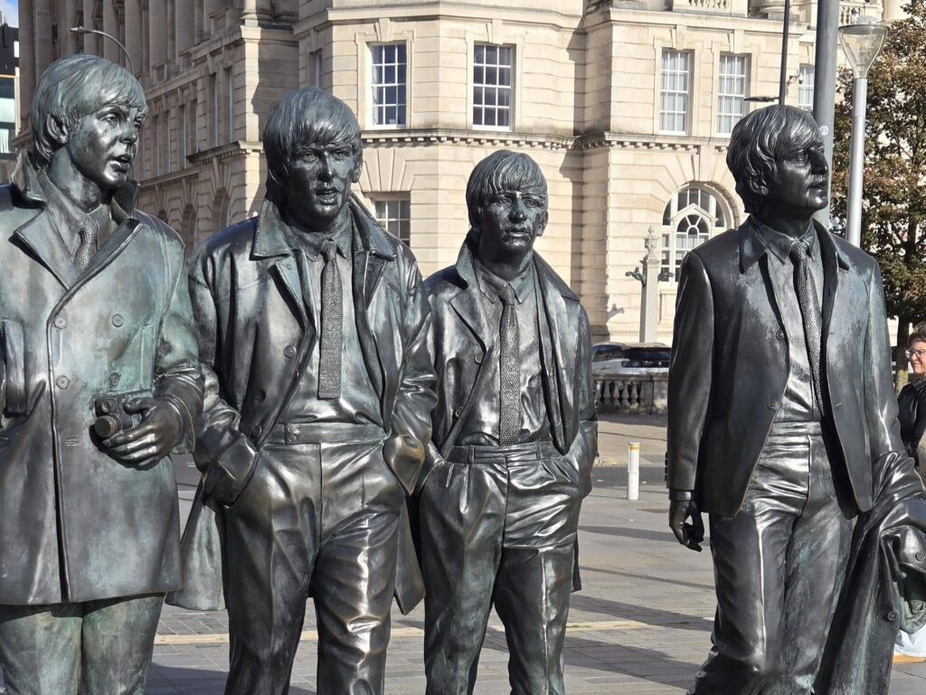 Bronze statues of four musicians walking together.