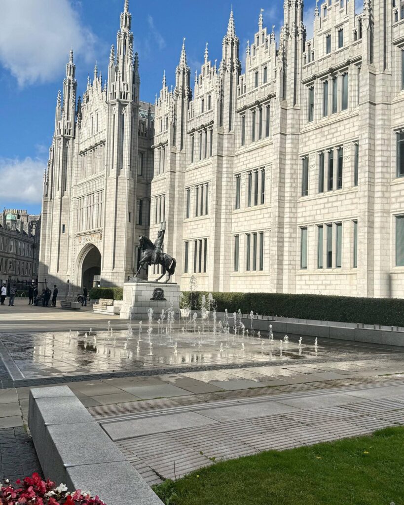 Historic building with statue and water fountains.