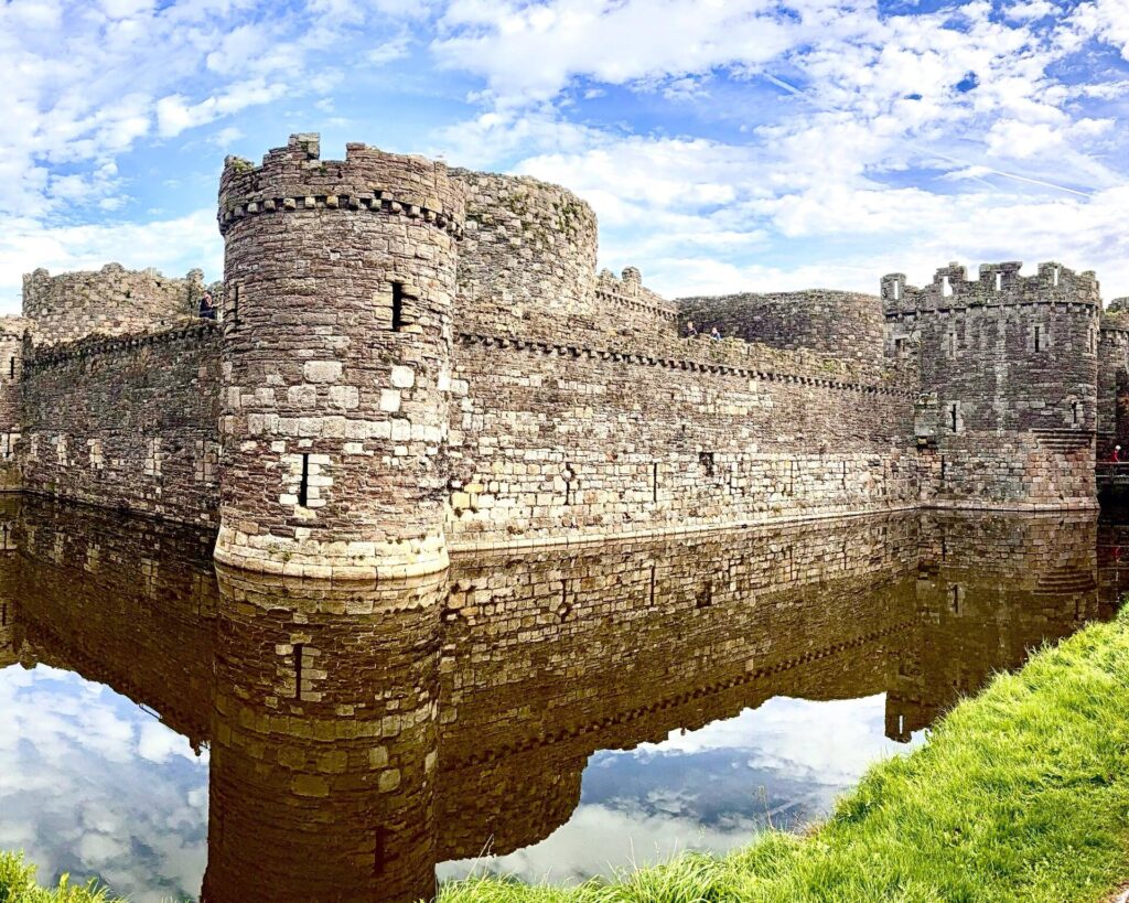 Historic stone castle with moat, under blue sky.