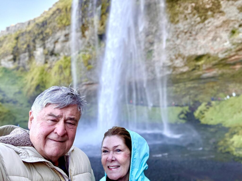 Couple smiling in front of a waterfall