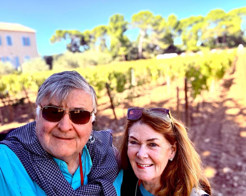 Smiling couple in sunny vineyard scene.