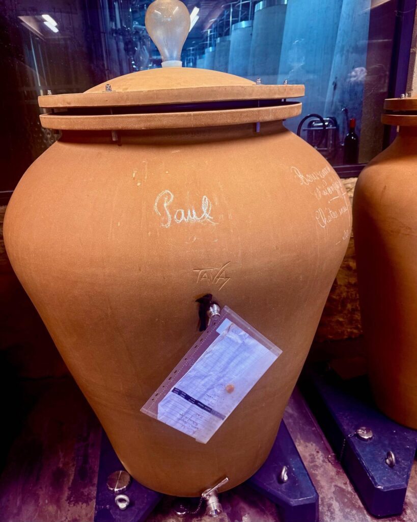Large clay wine barrel with a valve and label.