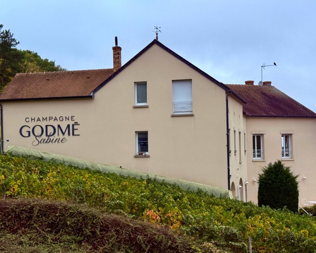 Champagne vineyard building with signage and vines.