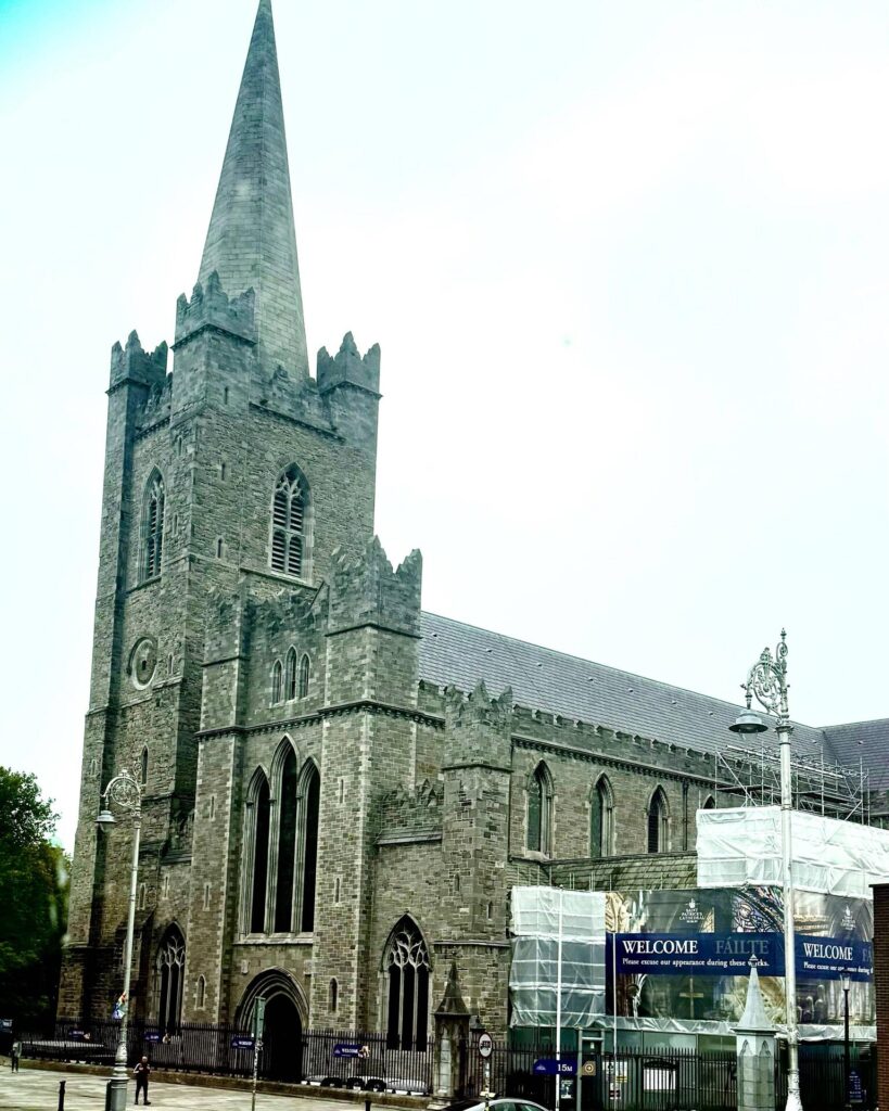 Historic stone cathedral with tall spire in overcast sky.